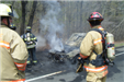 3 firefighters next to car covered in grey soot