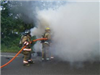 firefighters holding a fire hose in front of smoke