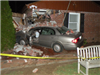 grey car crashed into brick house