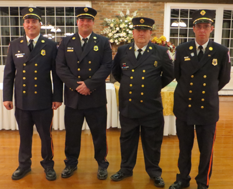 4 men in blue navy uniforms standing by each other