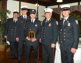 5 firefighters with one holding a plaque
