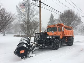 This is an image of an orange Mack truck snowplow.