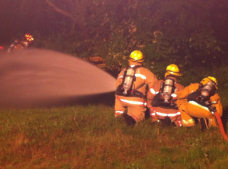 3 firefighters shooting water from a hose