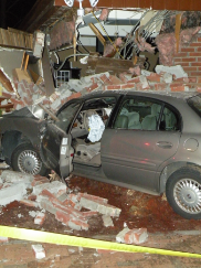 grey car crashed into brick house