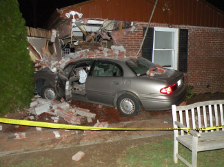 grey car crashed into brick house