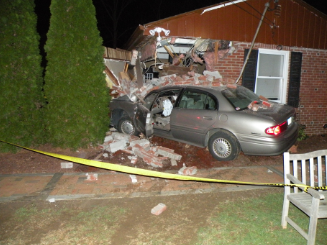 grey car crashed into brick house